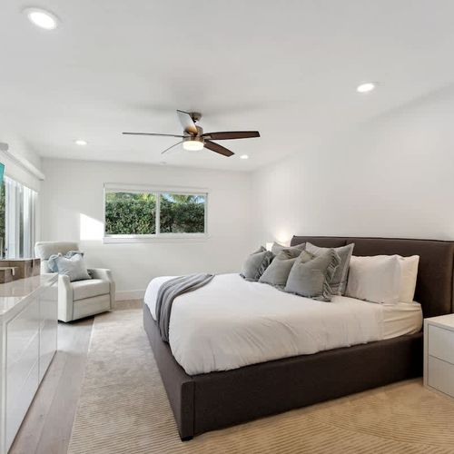 Primary bedroom featuring a king-size bed, ensuite bathroom, comfortable seating, and a large TV.