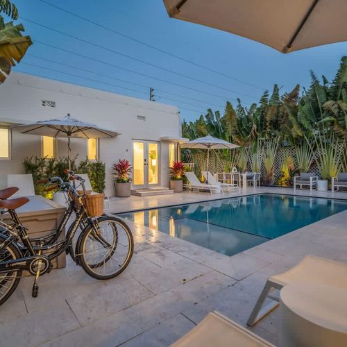 Tropical courtyard pool surrounded by palm trees and greenery, it truly feels like a hidden oasis in the middle of Miami Beach.