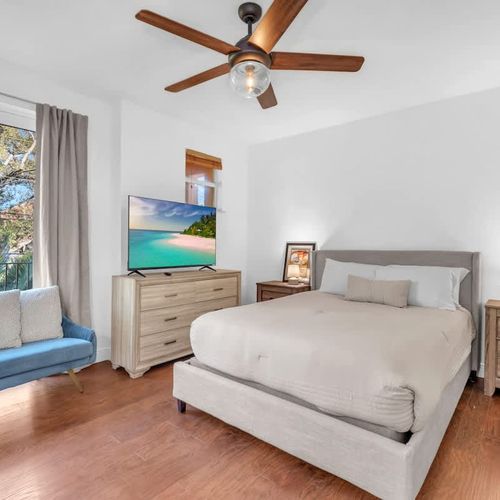 Enjoy Bedroom 2 with a comfy couch, TV, and sunlit windows overlooking peaceful outdoor scenery.