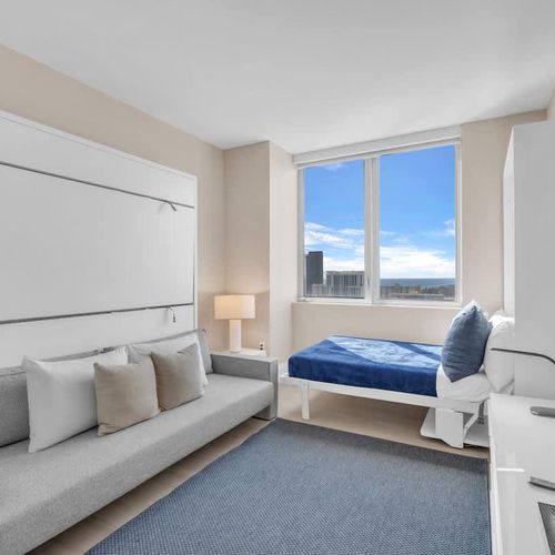 Bright and spacious Bedroom 3 featuring a comfortable bed by the window, plus a Murphy bed above the sofa on the left that folds down and is accessed by small steps.