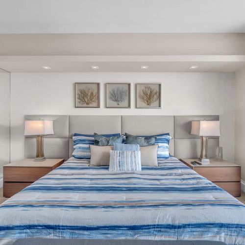 Modern, sunlit bedroom with a king-size bed, workspace, and private balcony offering beautiful ocean and city views. ️