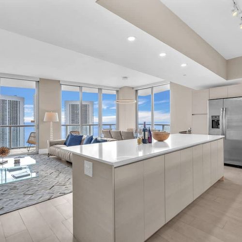 Spacious living area featuring a large flat-screen TV and a modern kitchen with a breakfast counter and stylish bar seating.