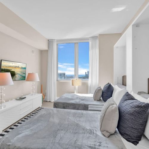 This second bedroom includes two full-size beds and its own TV, creating a cozy and convenient space for children or companions.