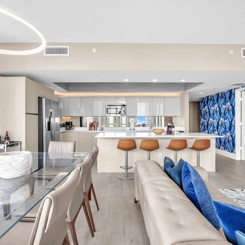 Elegant dining area featuring a modern glass table with seating for up to 8 guests, offering a comfortable setting for shared meals.