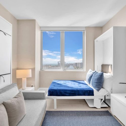 Bright and spacious Bedroom 3 featuring a comfortable bed by the window, plus a Murphy bed above the sofa on the left that folds down and is accessed by small steps.