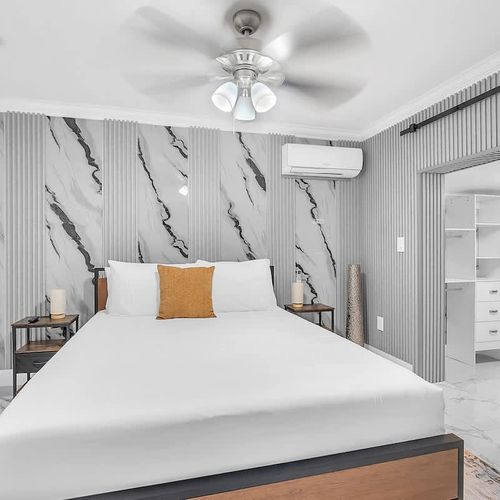 Elegant bedroom with a striking marble-style feature wall, comfortable bedding, and contemporary finishes.