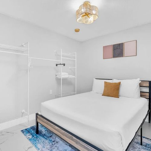 Cozy, minimalist bedroom with a comfortable bed, soft linens, and open closet space for easy unpacking.