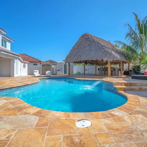 Private resort-style pool with spacious patio and a beautiful tiki hut lounge area.