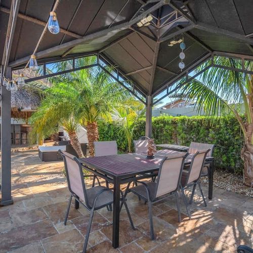 Shaded patio dining space surrounded by palm trees for relaxed outdoor meals.