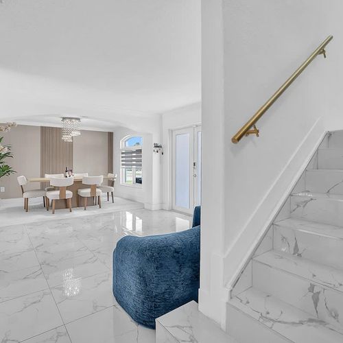 Sleek staircase with marble-style steps and elegant gold handrail. Bright, open entryway leading to a stylish dining area with modern finishes.