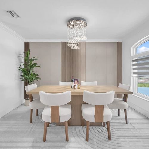 Elegant dining area with a modern table for six, statement chandelier, and large windows bringing in natural light.
