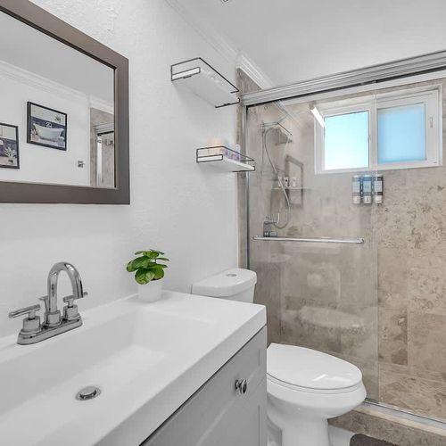 Clean and bright bathroom featuring a large vanity, glass shower, and modern finishes throughout.