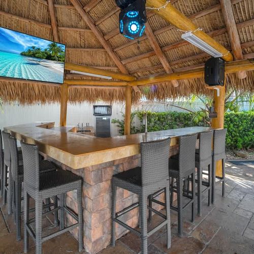 Tropical-style tiki bar with seating and TV—perfect for entertaining poolside.