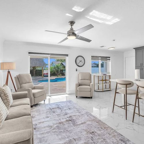 Bright and airy living room with comfortable seating, smart TV, and direct access to the pool area through sliding glass doors.