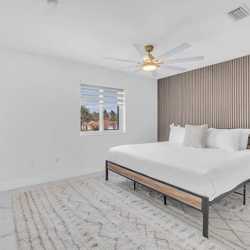 Spacious bedroom featuring a sleek platform bed, neutral tones, and a calming, minimalist design.