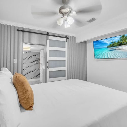 Stylish bedroom with a sleek accent wall, sliding barn door, and mounted TV for a relaxing stay.