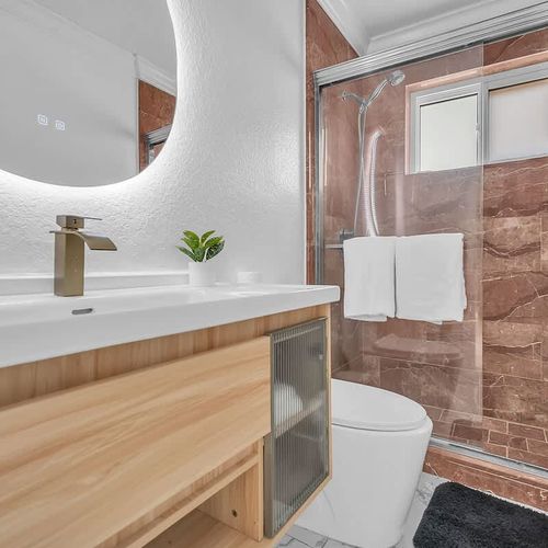 Sleek bathroom with a contemporary vanity, illuminated mirror, and stylish tiled walk-in shower.