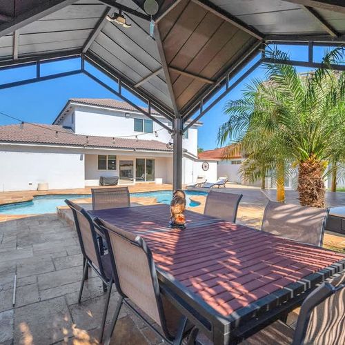 Outdoor dining under a covered terrace overlooking the private pool and tropical landscaping.
