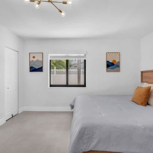Spacious primary bedroom featuring a king-size bed, private ensuite bathroom, and direct access to the pool area.