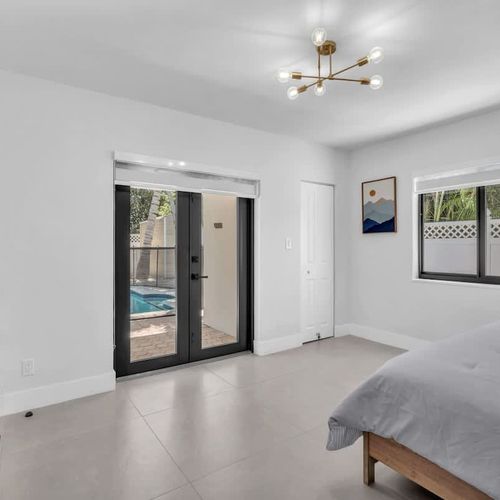 Spacious primary bedroom featuring a king-size bed, private ensuite bathroom, and direct access to the pool area.