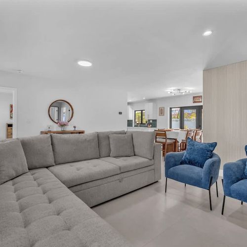 Modern and inviting living room featuring a large smart TV with a stylish wood accent wall, plus a comfortable sleeper sofa that easily accommodates up to two additional guests.