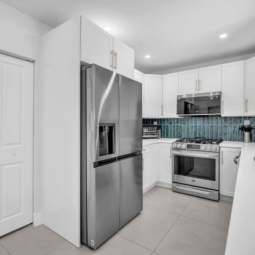 Prepare everything from full home-cooked meals to quick poolside snacks in this bright modern kitchen featuring updated appliances, generous counter space, and a fresh coastal-inspired design.