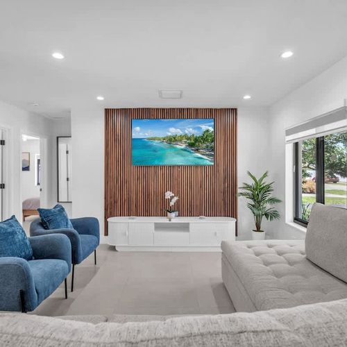 Modern and inviting living room featuring a large smart TV with a stylish wood accent wall, plus a comfortable sleeper sofa that easily accommodates up to two additional guests.