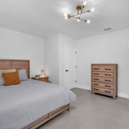 Spacious primary bedroom featuring a king-size bed, private ensuite bathroom, and direct access to the pool area.