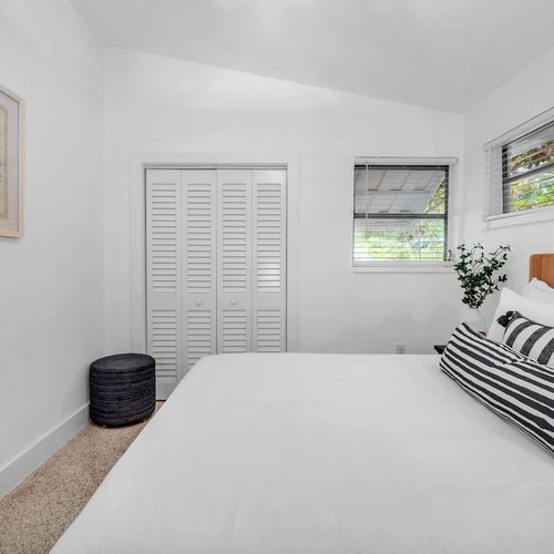 Cozy and airy Bedroom 2 featuring a Queen sized bed framed by warm wooden tones and coastal artwork.