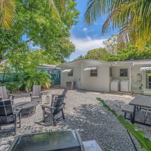 Private backyard retreat featuring a firepit with seating, picnic-style dining table, and a grill for al fresco cooking under the palms.