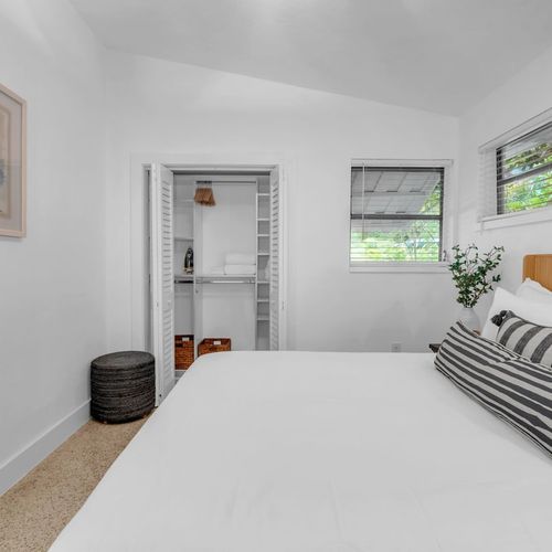 Cozy and airy Bedroom 2 featuring a Queen sized bed framed by warm wooden tones and coastal artwork.