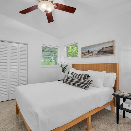 Cozy and airy Bedroom 2 featuring a Queen sized bed framed by warm wooden tones and coastal artwork.