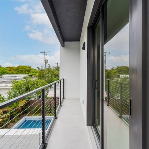 Step outside and breathe in the fresh air on this sleek, modern balcony. Featuring contemporary cable railings and clean architectural lines, this elevated space offers a perfect view overlooking the pristine swimming pool and lush greenery below.