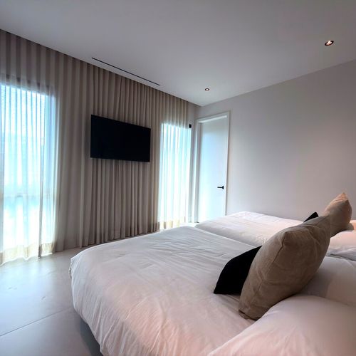 Featuring twin beds, modern minimalist art, and a large flat-screen TV, this room is the ultimate setup for guests or kids. Floor-to-ceiling windows keep the space bright, airy, and inviting.