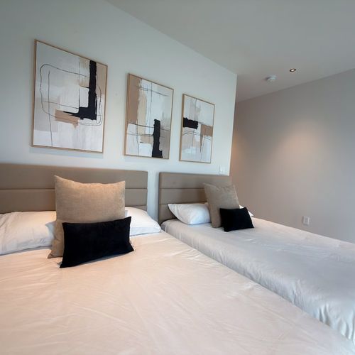 Discover comfort and versatility in Bedroom 3. This bright, modern space is thoughtfully styled with dual beds, neutral-toned accent pillows, and contemporary decor.