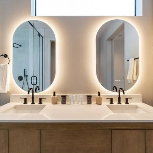 Full Bathroom 1 features a luxurious freestanding soaking tub, a sleek double vanity with glowing backlit mirrors, and an expansive walk-in glass shower. Modern luxury at its finest.
