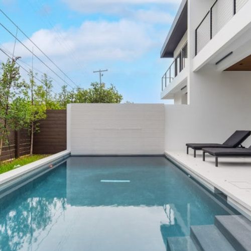 Escape to your own private paradise. This spectacular backyard oasis features a pristine, crystal-clear swimming pool surrounded by a sleek sun deck and comfortable lounge chairs.