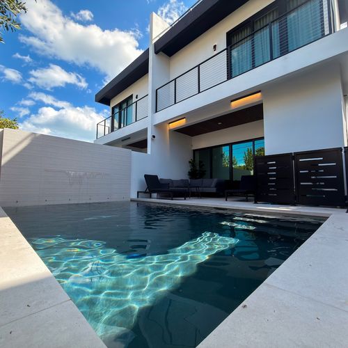 Experience seamless indoor-outdoor living in this masterfully designed modern backyard. The property boasts a luxury inground pool with crisp white architectural lines, flanked by a dedicated poolside lounge area.
