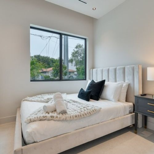 Bedroom 4 showcases sophisticated minimalist design and premium finishes. The room is anchored by a stylish channeled headboard and complemented by sleek dark nightstands.
