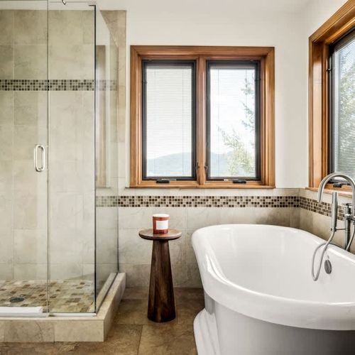 Primary bedroom's private full ensuite bathroom with walk-in glass shower and soaking tub