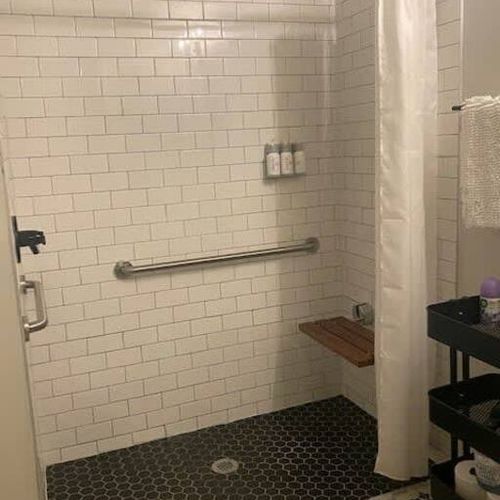 The room has a wheelchair accessible shower with handle bars and a bench seat.