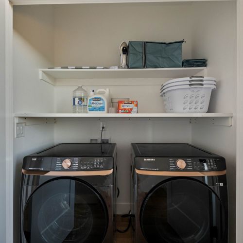 In-unit laundry with detergent, towels, and shelves for guest use.