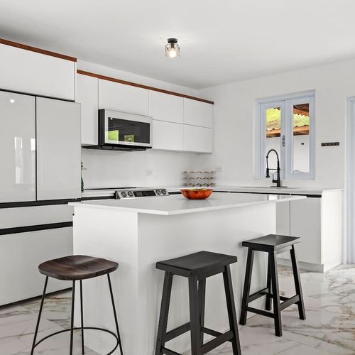 A spacious wooden dining table with access to the balcony with views, with marble flooring,, natural plants. lots of natural light and incredible views. white  kitchen with large countertop for big families. microwave, double door fridge with freezer