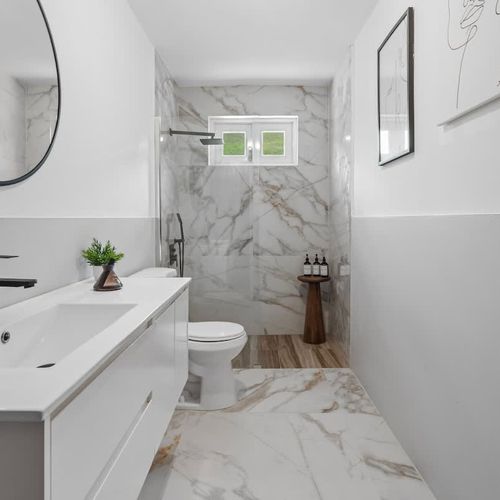 A well-lit bathroom featuring a vanity, toilet, and shower.