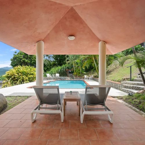 Lounge chairs await under a shaded gazebo overlooking a serene pool