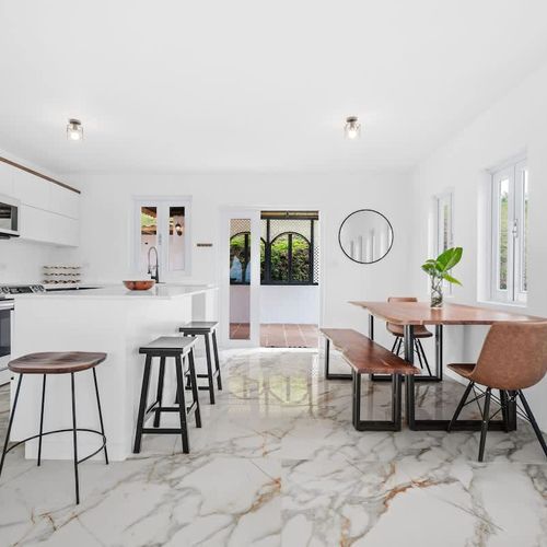 A spacious wooden dining table with access to the balcony with views, with marble flooring,, natural plants. lots of natural light and incredible views. white  kitchen with large countertop for big families. microwave, double door fridge with freezer