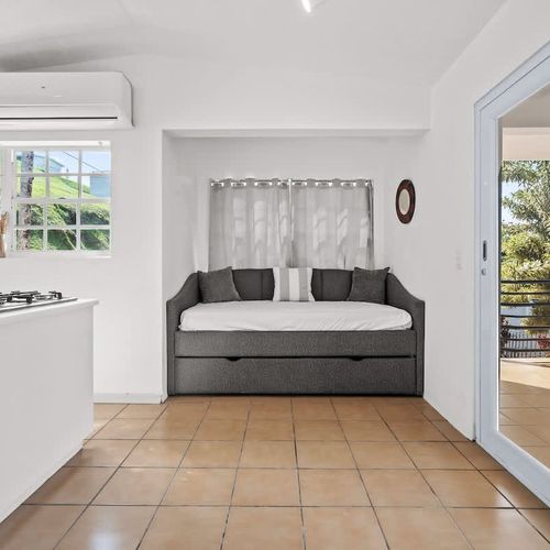 A bright and spacious room with a kitchenette, a sofa bed, and large sliding glass doors leading to a balcony with scenic views.