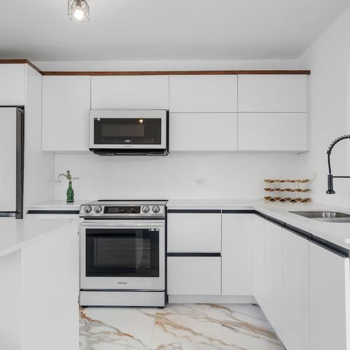 Modern and spacious white kitchen with stove, microwave, oven, double door fridge with freezer, wide dishwasher, access to bbq area