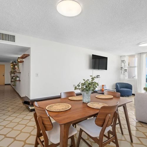 Dine with a view! This open-concept living and dining area provides a perfect space for shared meals, with glimpses of the ocean adding to the inviting ambiance.