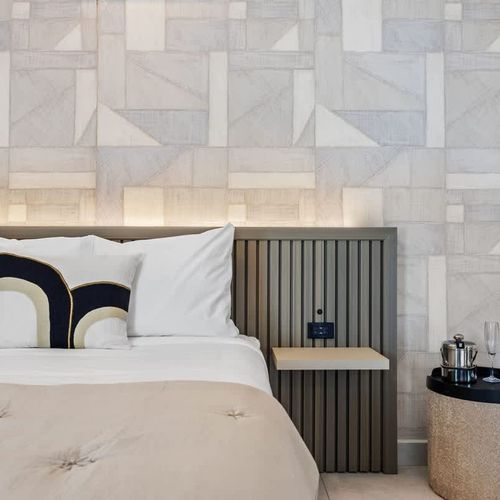 Chic accommodation showcasing a spacious bed flanked by contemporary nightstands, each equipped with reading lamps for late-night relaxation.